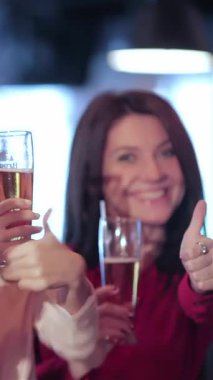 Genç yetişkinlerden oluşan canlı bir üçlü, iki kadın ve bir erkek, canlı bir barda en sevdikleri futbol takımlarının zaferini kutlamak için buz gibi bardaklarla coşkuyla tezahürat yapıyorlar. Işıl ışıl gülüşleri ve coşkulu başparmak kaldırışları...