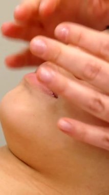 An expert massage therapist lovingly caresses a young girls forehead in a tranquil beauty salon, enveloping the scene in a soothing ambiance. The close-up highlights the delicate, nurturing hands gliding over the girls flawless skin, evoking