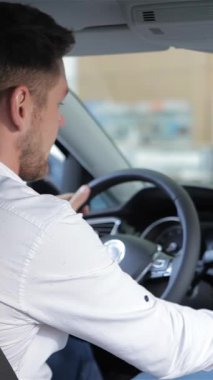 Modern bir araba konsolunun dokunmatik ekranıyla meşgul olan şık sakallı neşeli bir beyaz adam, heyecan dolu bir şekilde ışıldıyor. Baş parmak hareketi coşku saçıyor. Son teknolojiyi keşfetmenin heyecanını mükemmel bir şekilde yakalıyor.