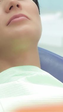 A dedicated dentist carefully adorns a lovely young woman with striking red protective glasses while she relaxes in the dental chair, ready for her checkup. This serene scene embodies the essence of professional dental care, showcasing the girls