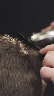 A close-up shot reveals the deft hands of a barber expertly trimming a clients hair with precision clippers, capturing the artistry of grooming in a stylish barbershop. The atmosphere exudes professionalism and elegance, showcasing the intimate bond