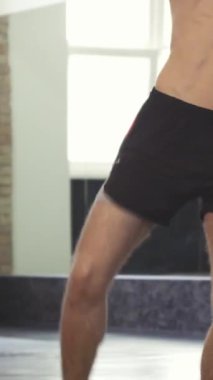 A powerful kickboxer, showcasing his chiseled physique, delivers explosive kicks to the pads held by his focused coach in a sleek, modern gym. The atmosphere is charged with energy and determination, highlighting the athletes commitment to mastering