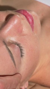 A mature woman revels in the calming embrace of a tranquil spa, as skilled hands gently massage her head and face, melting away tension and stress. The soft, ambient lighting and serene atmosphere create a haven of relaxation, inviting a deep sense