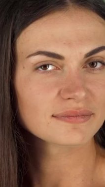 A joyful young woman radiates happiness as she playfully tucks a vivid red flower into her long, flowing hair, set against a lively green backdrop. Her warm smile and sparkling eyes reflect a carefree spirit, inviting viewers to embrace the beauty of