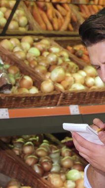 Zarif bir beyaz adam, hafif bir gülümseme ile, süpermarkette canlı bir dizi taze ürünle çevriliyken not defterine notlar yazmaya daldı. Titiz bir alışveriş listesi hazırlarken kalemi sayfa boyunca süzülüyor.