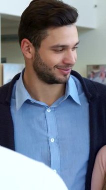 A stylish Caucasian woman radiates joy as she gleefully accepts the car keys from a sharply dressed salesman, while her handsome brunette partner admires her with a proud smile. The bustling dealership, filled with sleek vehicles and a vibrant