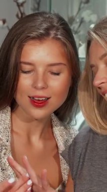 Two fashionable young women share a delightful moment as they try on stunning diamond rings in a sophisticated jewelry store. Their radiant smiles and infectious laughter illuminate the space, capturing the essence of friendship and the joy of