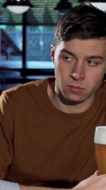 Sıcak, loş bir barda, düşünceli bir suratı olan yakışıklı genç bir adam sakallı arkadaşının yanında oturur ve bir bardak bira eşliğinde samimi bir anı paylaşır. Arkadaşlığın karmaşıklıklarında yol alırken ortam duygularla doludur.