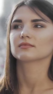 Güzel genç bir kadın düşünceli bir şekilde uzaklığa bakar, canlı bir şehir manzarasında birini bekler. Yumuşak güneş ışığı, onun doğal güzelliğini ve özgüvenini arttırarak, hayat dolu şehir hayatının ortasında duruyor.