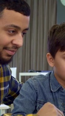 Rahat, modern bir dairede, esmer saçlı genç bir çocuk zarif bir dizüstü bilgisayarın üzerinde özenle, özenli Afrikalı Amerikalı babası ona gülümseyip rehberlik ederken. Bu dokunaklı an öğrenme ve takım çalışması yoluyla aralarındaki bağı güzel bir şekilde gösteriyor.