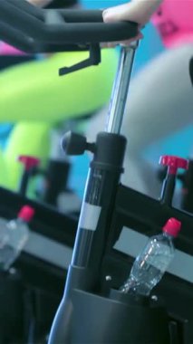 Atletik kız arkadaşlardan oluşan dinamik bir dörtlü hareketsiz bisikletler üzerinde güçlü bir şekilde pedal çeviriyor, hareketli bir spor salonunda enerji ve kararlılık yayıyor. Renkli spor kıyafetleri ve odaklanmış ifadeleri takım çalışmasının ve bağlılığın ruhunu güçlendirir.