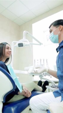 In a sleek, modern dental clinic, a cheerful young dentist in a mask and gloves shares an enthusiastic thumbs-up with a smiling female patient. Their vibrant expressions and the bright, airy environment radiate positivity and confidence, showcasing a