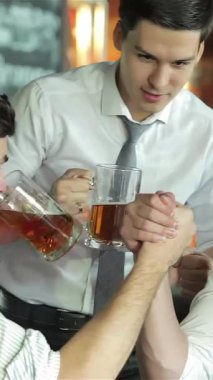 Three enthusiastic businessmen, dressed in smart casual attire, raise their frosty beer mugs in a vibrant bar, sharing hearty laughter and excitement as they cheer for their favorite football team on the big screen. The lively atmosphere buzzes with