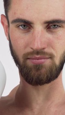 A confident bearded male boxer flashes a charismatic smile while poised in a dynamic fighting stance, showcasing his boxing gloves and athletic physique. His piercing eyes and determined expression radiate strength and readiness, embodying the fierce