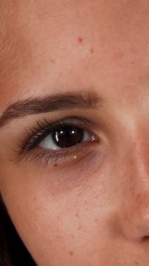 A stunning close-up captures a joyful young woman with flawless skin, beaming at the camera against a lush green backdrop. Her natural beauty radiates confidence and positivity, showcasing her carefree spirit and vibrant energy