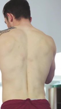 In a vibrant gym filled with energy, a strong young man, tattooed and focused, engages in a dynamic sparring session with his coach. The atmosphere crackles with intensity as they push each other to excel, embodying the spirit of professional boxing