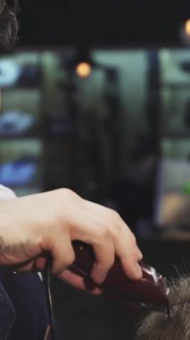 In a chic barbershop, a focused barber with a stylish tattoo skillfully trims his clients hair, showcasing precision and artistry. The inviting atmosphere, enriched by warm lighting and vintage decor, creates a perfect backdrop for modern grooming
