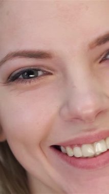 Çekici bir yakın plan, beyaz tenli güzel bir kadın, kameraya sıcak, dişlek bir gülümseme yansıtıyor. Yumuşak sarı saçlarıyla çerçevelenmiş kusursuz yüzüne dokunuşu saf beyaz bir kadına karşı özgüven ve zarafet saçıyor.