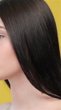 Büyüleyici bir Asyalı kadın zarif bir şekilde sarı bir arkaplanda poz veriyor. Parmağı zarif bir şekilde tatlı dudaklarına bastırıyor ve sessiz bir jest yapıyor. Uzun, pürüzsüz saçları zarif bir şekilde dalgalanırken cazibe ve cazibe saçıyor.