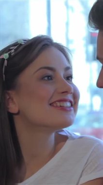 Bu büyüleyici yakın plan, büyüleyici bir kafede hoş bir sohbete dalmış gülümseyen bir çifti yakalıyor. Esmer adam uzanıyor ve uzun saçlı, güzel beyaz kız arkadaşıyla bir hikaye anlatıyor. Parlak gülümsemesi saf mutluluğu yansıtıyor.