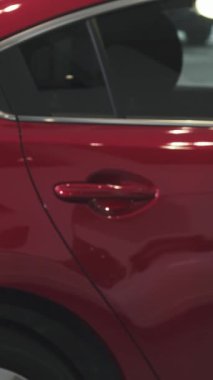 Heyecanlı bir kadın, galerideki arkadaş canlısı bir satıcıdan çarpıcı yeni kırmızı arabasının anahtarlarını memnuniyetle kabul ederek otomotiv yolculuğunda önemli bir ana imza atıyor. Işıldayan araç arka planda parıldıyor, neşeyi arttırıyor ve