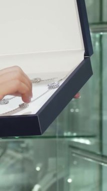 Havalı saçlı şık bir kadın lüks bir mücevher kutusuna yerleştirilmiş nefes kesici bir kolyeye hayranlıkla bakıyor. Heyecan ve neşe saçıyor. Bu canlı sahne, etrafını sarmış şık bir butikte zarif mücevher seçeneklerini keşfederken onun zevkini yakalıyor.