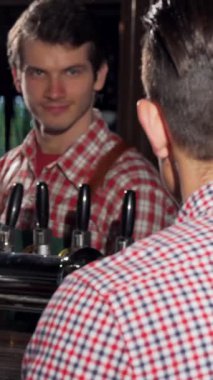 Çekici bir genç adam canlandırıcı bir biradan zevk alır, şık bir barda arkadaşıyla canlı bir sohbet eder, parlak ahşap ve musluklar sıcak, davetkar bir atmosfer yaratır. Arkadaşlığın ve kutlamanın enerjik enerjisi havayı dolduruyor.