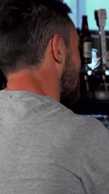 Gri gömlekli şık bir genç adam, her biri soğuk bir bardak bira tutan samimi bir barda arkadaşıyla samimi bir gülüşü paylaşıyor. Sıcak ışıklandırma ve canlı atmosfer rahatlama ve dostluk için davet edici bir zemin oluşturur.