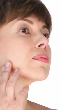 Işıl ışıl, 40 yaşında bir kadın kusursuz yüzünü nazikçe okşuyor, kendine güveni ve doğal güzelliği yayıyor. El değmemiş beyaz bir arkaplanda duran bu büyüleyici portre, onun taze tenini ve zamansız zarafetini vurguluyor.