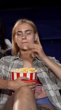 Çekici bir genç adam, sıcak bir sinemada iki güzel kadını kucaklıyor, kahkahaları bir film galasının heyecanı arasında yankılanıyor. Parlak atmosfer neşe ve sıcaklıkla dolu. Arkadaşlığın ve romantizmin güzelliğini vurguluyor.