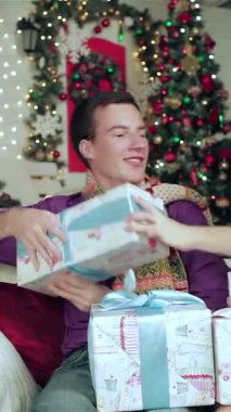 Keyifli bir çift, rahat kazaklara ve canlı eşarplara sarılı, güzel bir şekilde paketlenmiş Noel hediyelerini sıcak bir oturma odasında değiş tokuş ediyorlar. Büyüleyici sahne yanıp sönen ışıklar ve göz kamaştırıcı bir Noel ağacı ile aydınlatılır.