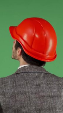Koyu kırmızı kasketli bir erkek müteahhit, canlı yeşil bir kromakey ekranı inceliyor. Bu dinamik imaj, inşaat endüstrisindeki yenilik ve profesyonelliğin ruhunu somutlaştırıyor.