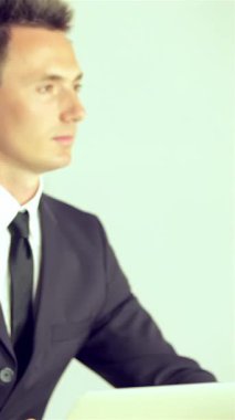 Two sharply dressed businessmen, one in a sleek black suit and the other in a stylish gray suit, are captivated by a speaker at a dynamic business forum. Their focused expressions and enthusiastic applause reflect a deep appreciation for the valuable