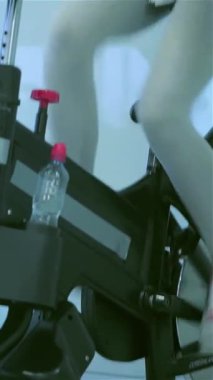 Enerjiyle dolu canlı bir spor salonunda, iki genç bayan spor bisikletleriyle neşeyle pedal çeviriyor, onların ışıl ışıl gülümsemeleri dostluk ve zindelik ruhunu yansıtıyor. Bu canlı sahne, renkli spor salonlarıyla çevrili atletik figürlerini hareket halinde yakalıyor.