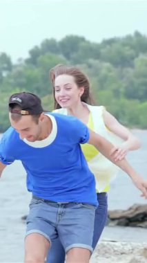 A carefree girl joyfully leaps onto her friends back, both bursting with laughter as they sprint along the sandy shore. This vibrant scene radiates the essence of friendship and summer joy, with sparkling waves and lush greenery framing their