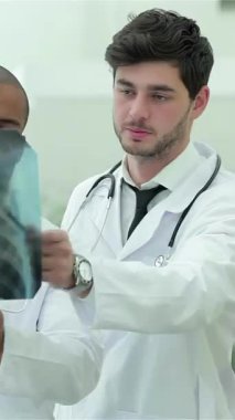 In a bright, modern clinic, three confident doctorstwo men and one womanintently analyze an x-ray of healthy lungs, showcasing their expertise and dedication. Their focused expressions and crisp white coats reflect professionalism, emphasizing the