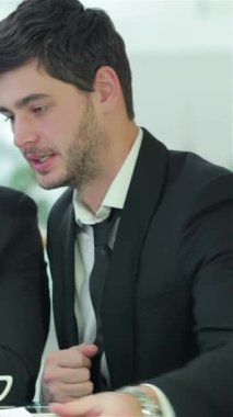 A group of four vibrant young professionals passionately engage in a lively discussion around a sleek, glass conference table, bathed in warm natural light pouring through expansive windows. Their animated gestures and bright smiles create an