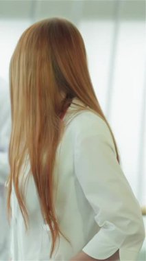 A confident woman in a crisp white lab coat gives a thumbs up, radiating positivity in a bright medical environment. Surrounded by two male doctors engaged in a discussion about an x-ray of healthy lungs, this scene embodies teamwork and dedication