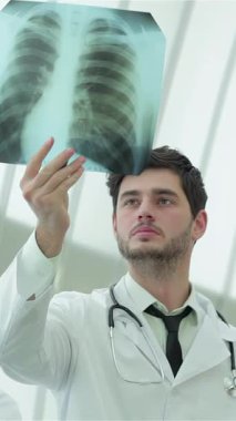 A focused male doctor, dressed in a crisp white coat and stethoscope, holds up a lung X-ray, emphasizing the severe risks of smoking. His intense gaze and professional demeanor create a compelling atmosphere of expertise and commitment to health