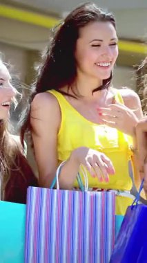 Three fashionable girls, each clutching vibrant shopping bags, radiate joy as they share laughter under the golden sun, creating an inviting and lively atmosphere. Their chic outfits and carefree demeanor embody the thrill of friendship and the