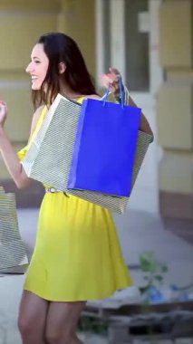 Three fashionable girls, each clutching colorful shopping bags, leap exuberantly on a sunlit street, exuding pure joy and a carefree spirit. Their infectious laughter fills the air as they celebrate their stylish finds, capturing the essence of