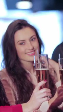 Neşeli bir üçlü, iki kadın ve bir erkek, bardaklarını canlı bir barda tokuştururlar, bulaşıcı kahkahalarla kutlarlar. Bar ışıklarının sıcaklığı ve heyecanın uğultusu en sevdikleri futbola kadeh kaldırırken elektrik atmosferi yaratır.