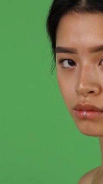 Parlak, uzun siyah saçlı, nefes kesici Asyalı bir kadın canlı yeşil bir renk perdesine karşı tutkuyla çığlık atıyor. Ham duygular fırtınasını somutlaştırıyor. Çarpıcı profili, öfke ve derin duygular arasında gidip gelen sert bir ifadeyi ortaya koyuyor.