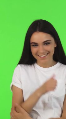 Parlak, beyaz tişörtlü esmer bir kadın neşe saçıyor, canlı yeşil bir arka plana başparmak sallıyor. Bulaşıcı gülümsemesi ve enerjik enerjisi pozitiflik ve başarı yayarak herkesi moral verici ruhunu paylaşmaya davet ediyor.