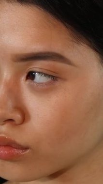 Kendine güvenen, dudak piercingli, ışıl ışıl gülümseyen genç bir Asyalı kadının çarpıcı yakın çekimi göz kamaştırıcı yeşil renkli bir arka plana dikkat çekiyor. Işıl ışıl cildi ve anlamlı gözleri neşe ve canlılık saçıyor.