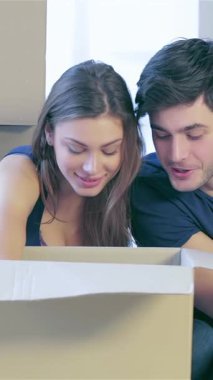 Neşeli bir çift yeni evlerinin zemininde oturmuş, zevkli hazinelerle dolu bir karton kutuyu hevesle keşfediyorlar. Etrafı boş duvarlarla ve istiflenmiş kutularla çevrili. Parlak gülümsemeleri ve ışıldayan gözleri yeni heyecanı yansıtıyor.