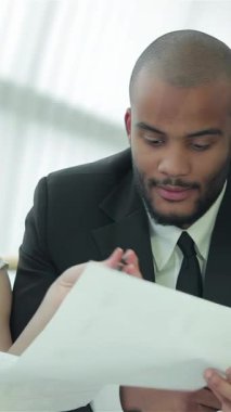 Aralarında kızıl saçlı bir kadının da bulunduğu dört kendinden emin iş adamından oluşan bir grup, zarif ve modern bir ofis masasında belgeleri tutkuyla tartışıyor. Animasyon jestleri ve parlak gülümsemeleri heyecan verici bir işbirliği atmosferi yaratıyor.