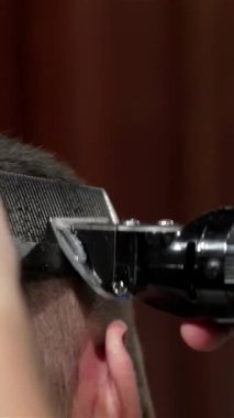 Şık bir berber dükkanında, yetenekli bir berber sakallı bir adamın saçını ustalıkla yontuyor, titiz bir hassasiyet ve yetenek sergiliyor. Sıcak ışıklandırma ve klasik aksanlarla zenginleşen davetkar atmosfer, tımar deneyimini geliştirir ve her kesiği atar.