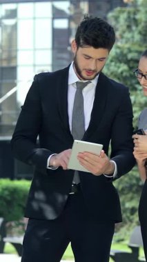 Kendine güvenen bir işadamı ve başarılı bir iş kadını şık bir tablet üzerinde canlı bir ofis alanına pozitiflik yayarak canlı bir işbirliğine girişirler. Şık, modern kıyafetleri ve ışıl ışıl gülümsemeleri takım çalışmasının ruhunu temsil ediyor.