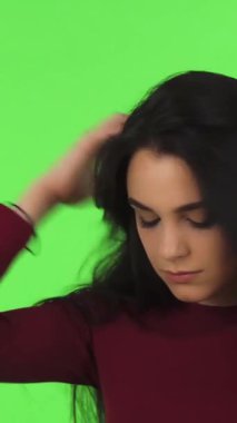 Göz kamaştırıcı, koyu renk saçları olan genç bir kadın elini nazikçe alnına koyar. Gözleri, çarpıcı bir yeşil zemine karşı kırılganlık anında kapalıdır. Bu çağrıştıran görüntü, duygusal acının ağırlığını güçlü bir şekilde aktarıyor.